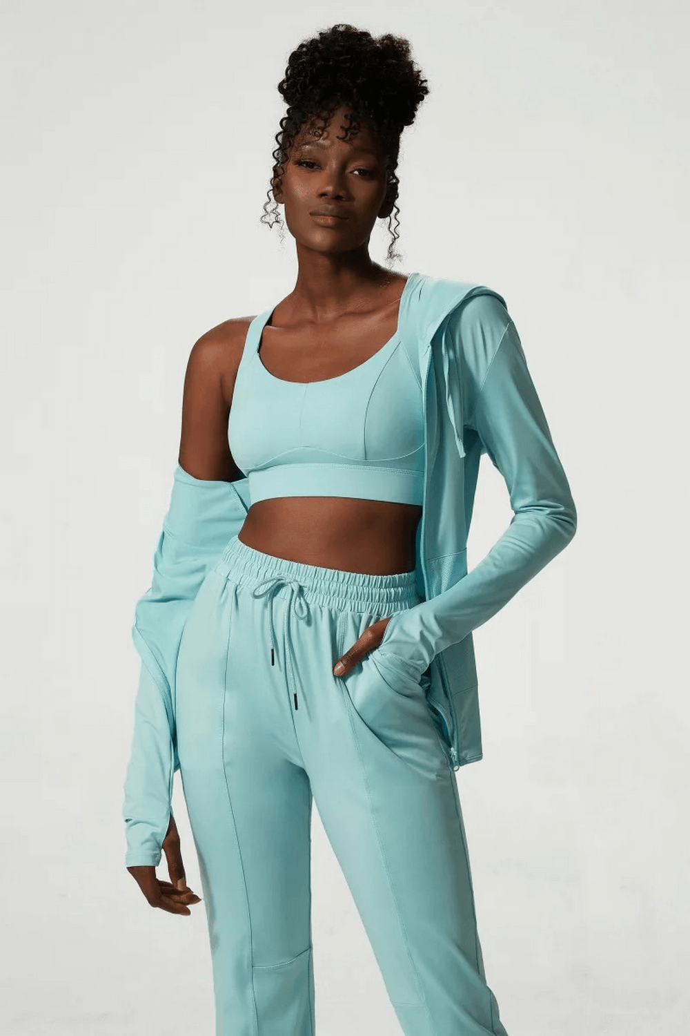 Woman modeling stylish three-toned athletic clothing set, featuring breathable, quick-drying, anti-wrinkle polyester fabric.